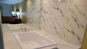 Une salle de bain moderne avec un grand miroir, une baignoire et un lavabo.