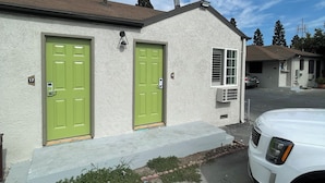 Un bâtiment à deux étages avec des portes vertes et une façade blanche.