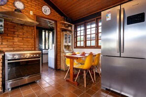 Une cuisine équipée d’un four Bosch, d’un réfrigérateur et d’une table à manger avec des chaises jaunes.