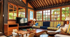 A cozy living room with a television, wooden furniture, and large windows. - Bz46 Casa 150 metros da praia 5 suites (Buzios)