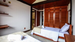 A bedroom with two beds, wooden wardrobes, and a small shelf. - Bz46 Casa 150 metros da praia 5 suites (Buzios)