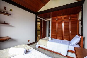 A bedroom with two beds, wooden wardrobes, and a small shelf. - Bz46 Casa 150 metros da praia 5 suites (Buzios)