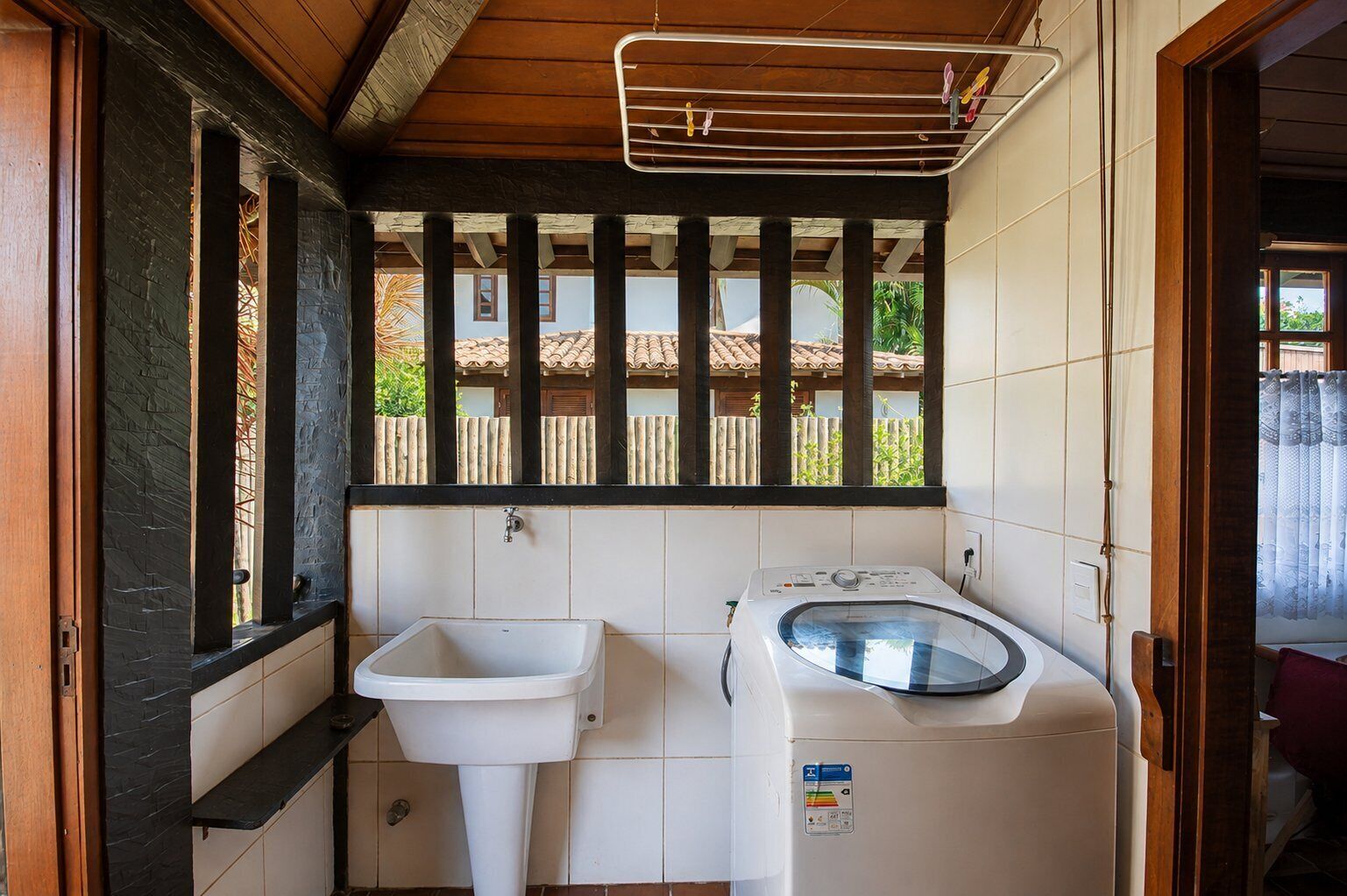 Ein kleines Badezimmer mit Waschbecken, Waschmaschine und Wäscheständer.