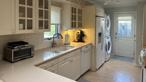A kitchen with white cabinets, a built-in oven, a sink, a dishwasher, and a washing machine. - Dog friendly Greenslake Cottage with lagoon view & community pool! King & Queen (Johns Island)