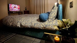Una habitación de hotel con cama, televisión, lámpara, planta y vela.