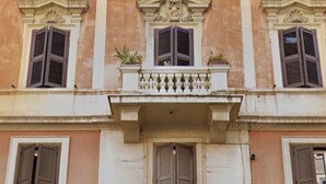 Un edificio con una entrada central, flanqueada por ventanas con contraventanas, y una placa sobre la puerta.
