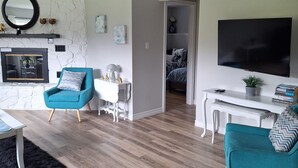A modern living room with a fireplace, a TV, and a cozy seating area. - Beautiful, cozy, spacious suite located central PEI. 3 bedrooms 4 beds.  (Lot 67)
