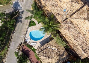 An aerial view of a property with a swimming pool, palm trees, and a tiled roof. - Bz47 Casa em João Fernandes Vista Mar (Buzios)
