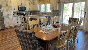 A spacious kitchen with white cabinetry, a central island, and a dining area with plaid chairs. - Family-friendly close to SDC, Branson, Eureka Springs, Table Rock, Roaring River (Cassville)