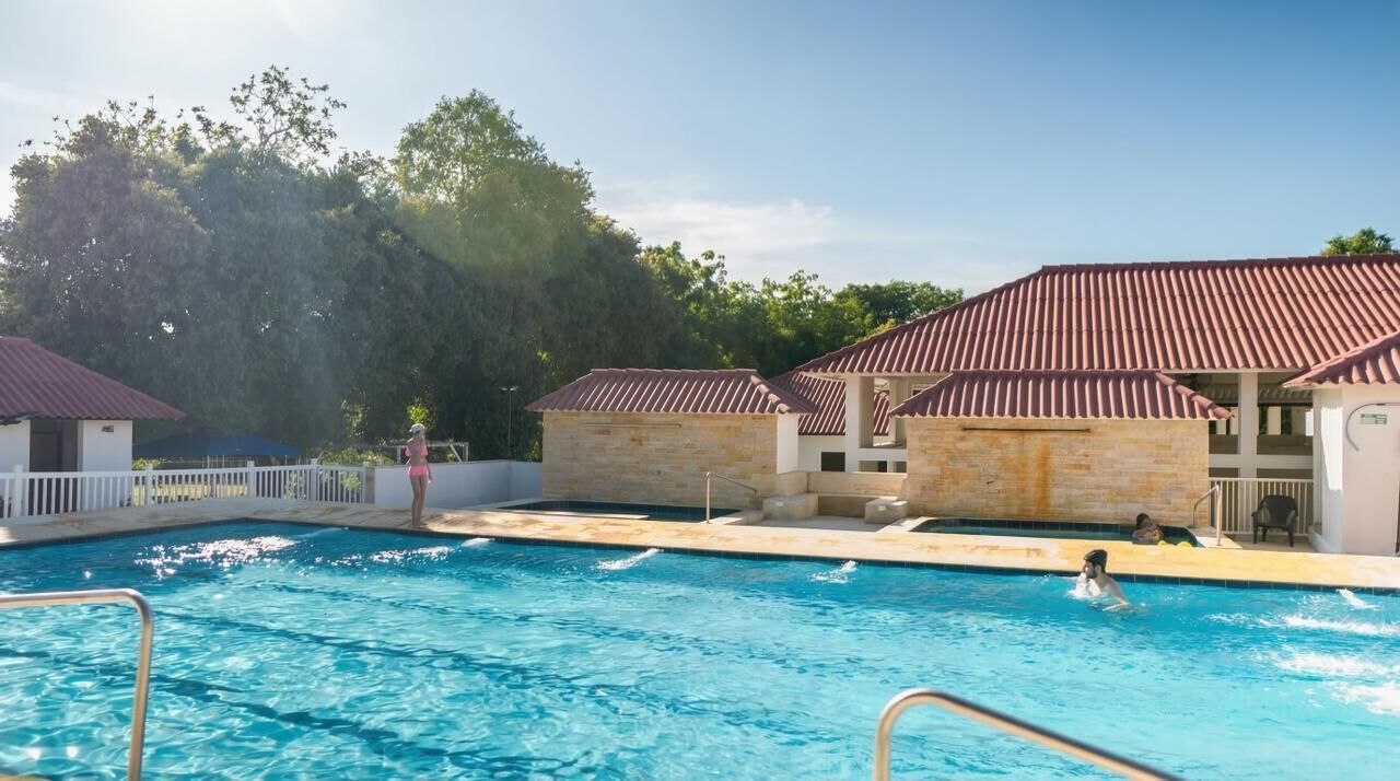 A swimming pool with clear water, surrounded by buildings with red roofs and stone walls.