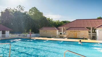 A swimming pool with clear water, surrounded by buildings with red roofs and stone walls.