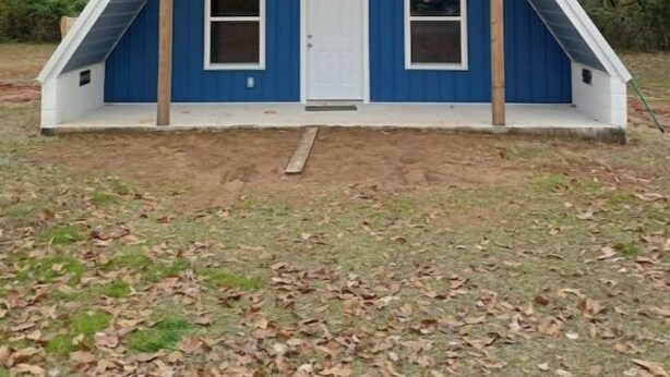 A blue, triangular-roofed building with a central door and two windows on each side. - Cedar Grove Rental A-frame (Clarksville)