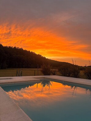 En swimmingpool med frit udsyn til solnedgang og det omkringliggende landskab.