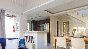 A modern living room with a sofa, a dining table set for four, and a kitchen in the background.