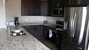 A kitchen with dark wooden cabinets, stainless steel appliances, granite countertops, and a built-in oven. - New 3BR w/ Garage, 1 Mile from Downtown (Hamilton)