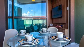 Una mesa con cubierta de vidrio, rodeada de sillas, con vista al exterior a través de un ventanal.