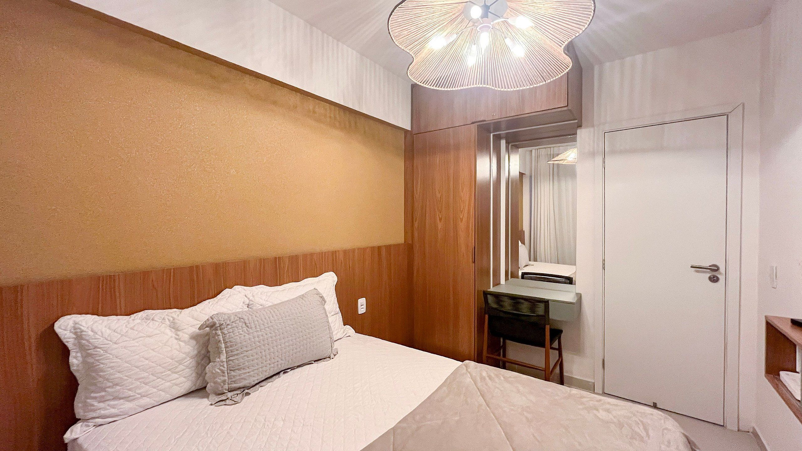 Una habitación de hotel con cama, mesita de noche, espejo y armario.