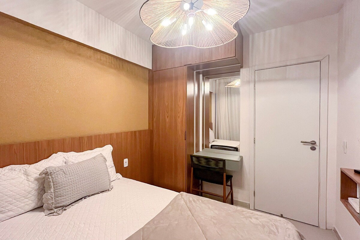 Una habitación de hotel con cama, mesita de noche, espejo y armario.