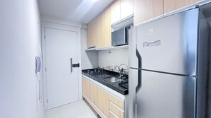 Een moderne keuken met een roestvrijstalen koelkast, een magnetron en een gasfornuis.
