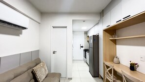 A narrow hallway with a sofa, a refrigerator, and a wooden shelf with a vase. - Açores Tamandaré Beach Beira-Mar (Tamandare)
