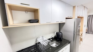 A compact kitchen with a gas stove, a coffee maker, a dish drying rack, and a refrigerator. - Açores Tamandaré Beach Beira-Mar (Tamandare)