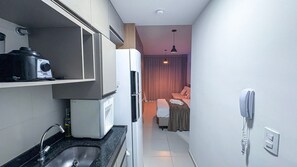 Habitación de hotel pequeña con kitchenette, cama y baño.