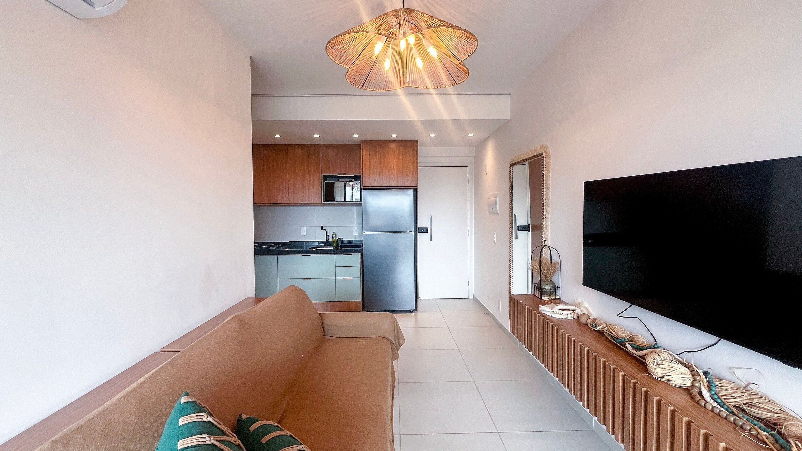 A modern living room with a sofa, a flat-screen TV, and a decorative wall.