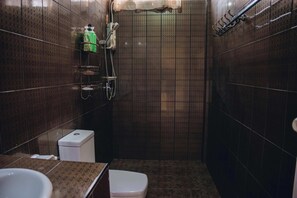 Pieni kylpyhuone, jossa on wc, pesuallas ja suihkutila.