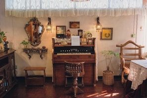 A room with a piano, a mirror, a small table, and a chair.