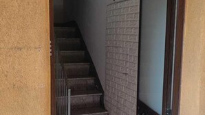 Una escalera que conduce a un piso superior con un muro de piedra y una puerta.