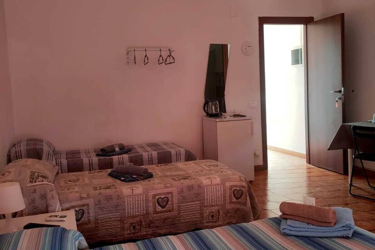 Un dormitorio con una cama, un escritorio, una silla, un espejo y una puerta.
