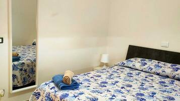 Una habitación de hotel con cama, espejo y mesita de noche con lámpara.