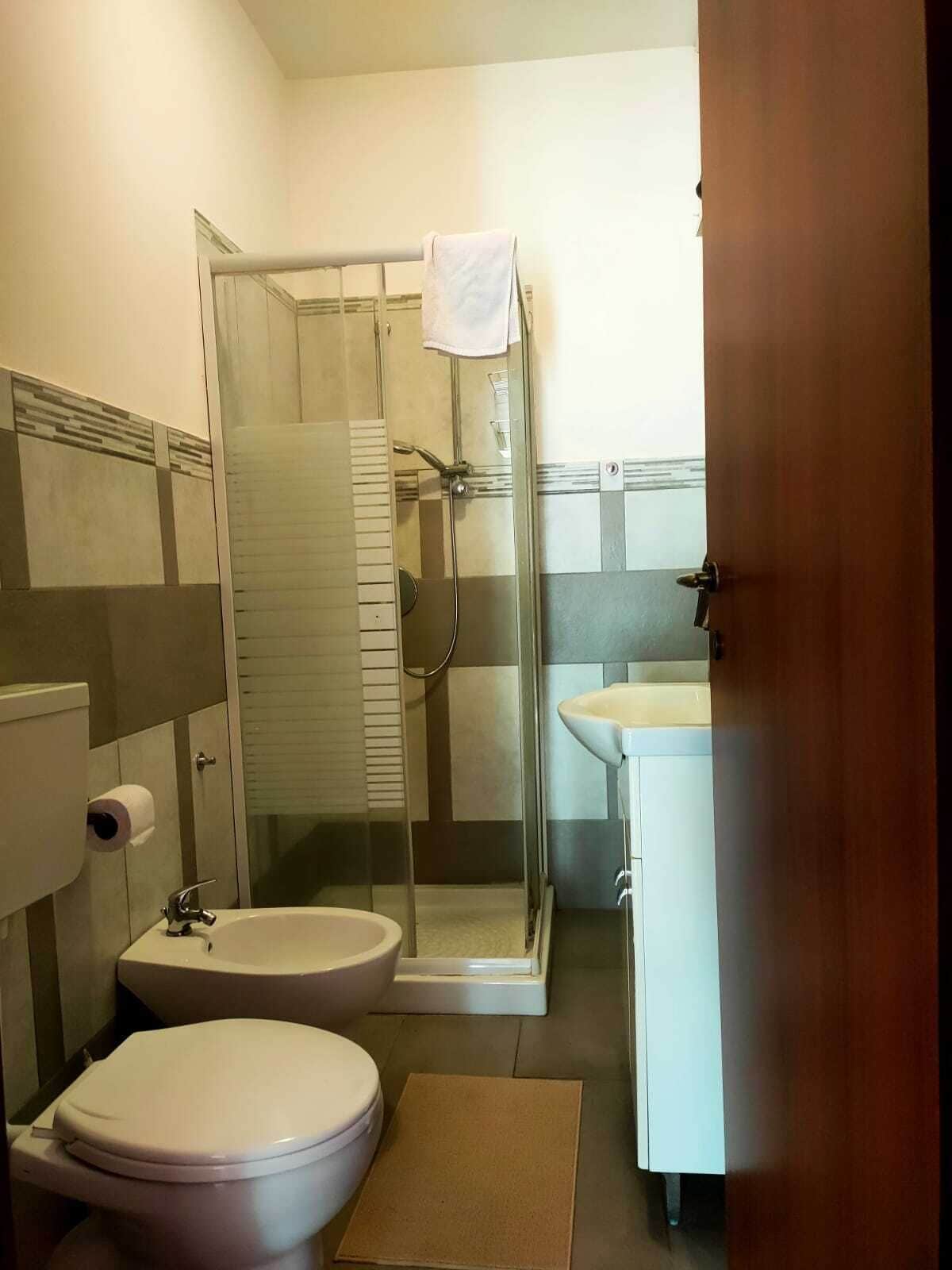 A bathroom with a toilet, a shower enclosure, and a sink.