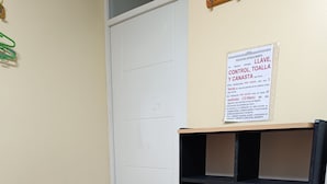 Ein Schlafsaalzimmer mit einem Etagenbett, einem Aushang an der Wand, einem Mülleimer und einer Tür.