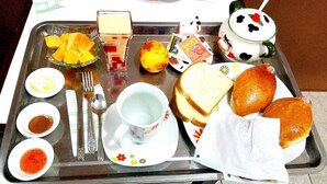 Ein Tablett mit Lebensmitteln, darunter Brot, eine Schale Obst und eine Tasse Tee.