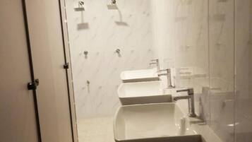 A modern bathroom with a large sink, a mirror, and a shower area.
