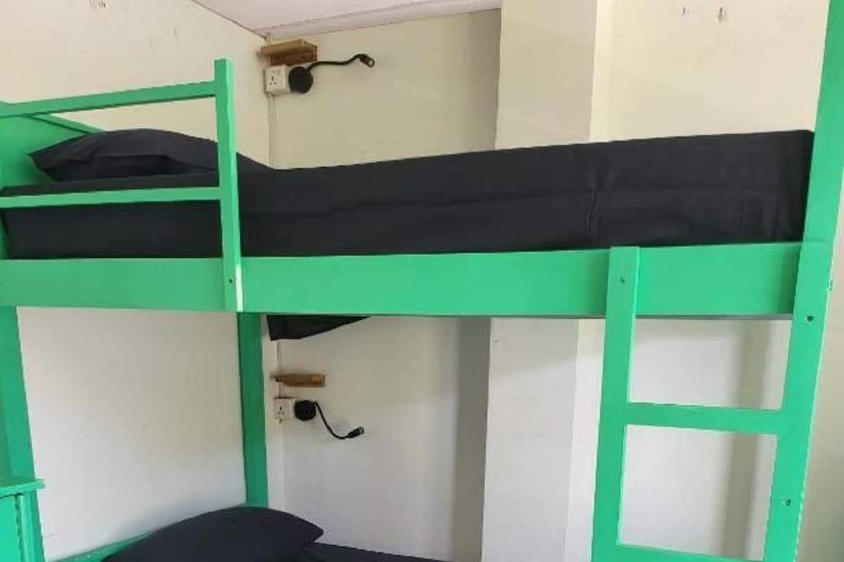 A bunk bed with a green frame and black bedding.