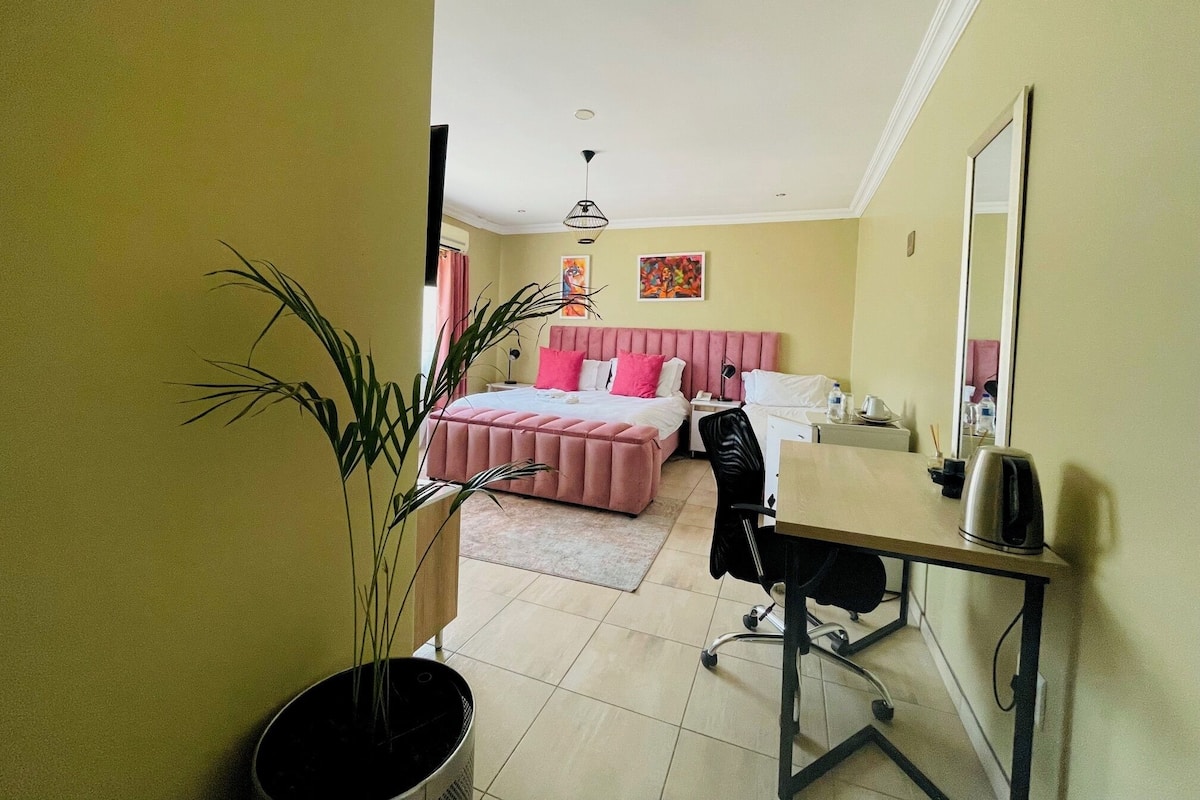 Una habitación de hotel con cama, escritorio, silla y una planta en maceta.