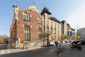 Un bâtiment historique à la façade en briques, doté de grandes fenêtres et d’une entrée située à l’angle.
