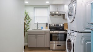 A compact kitchen with a built-in oven, a washing machine, and a sink. - Stylish Minimalist Stay in City Center (Philadelphia)