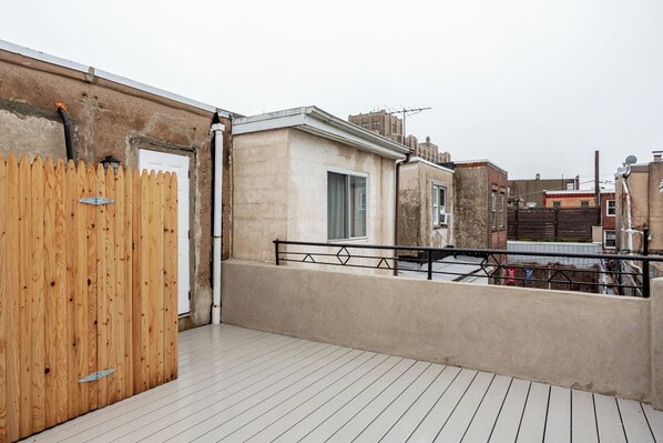 Eine Dachterrasse mit Holzzaun, Betonmauer und Metallgeländer.