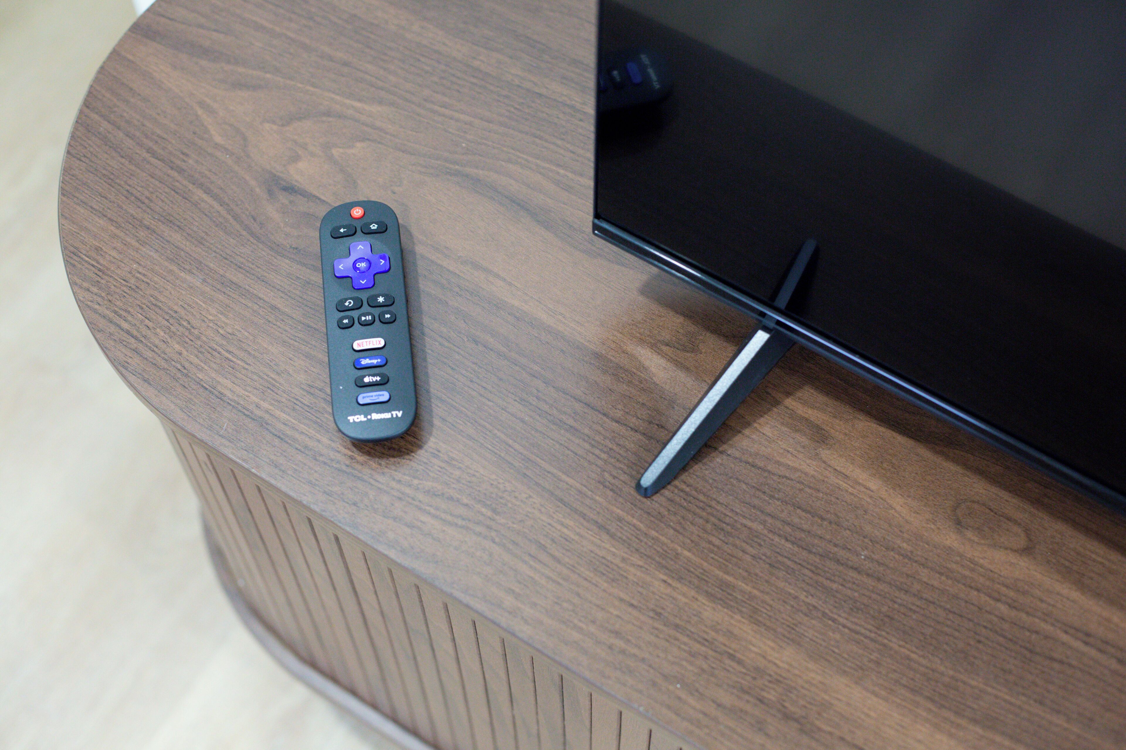 A remote control on a wooden surface next to a television.