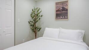 A bedroom with a bed, a poster of Mount Fuji, and a plant. - Stylish Minimalist Stay in City Center (Philadelphia)
