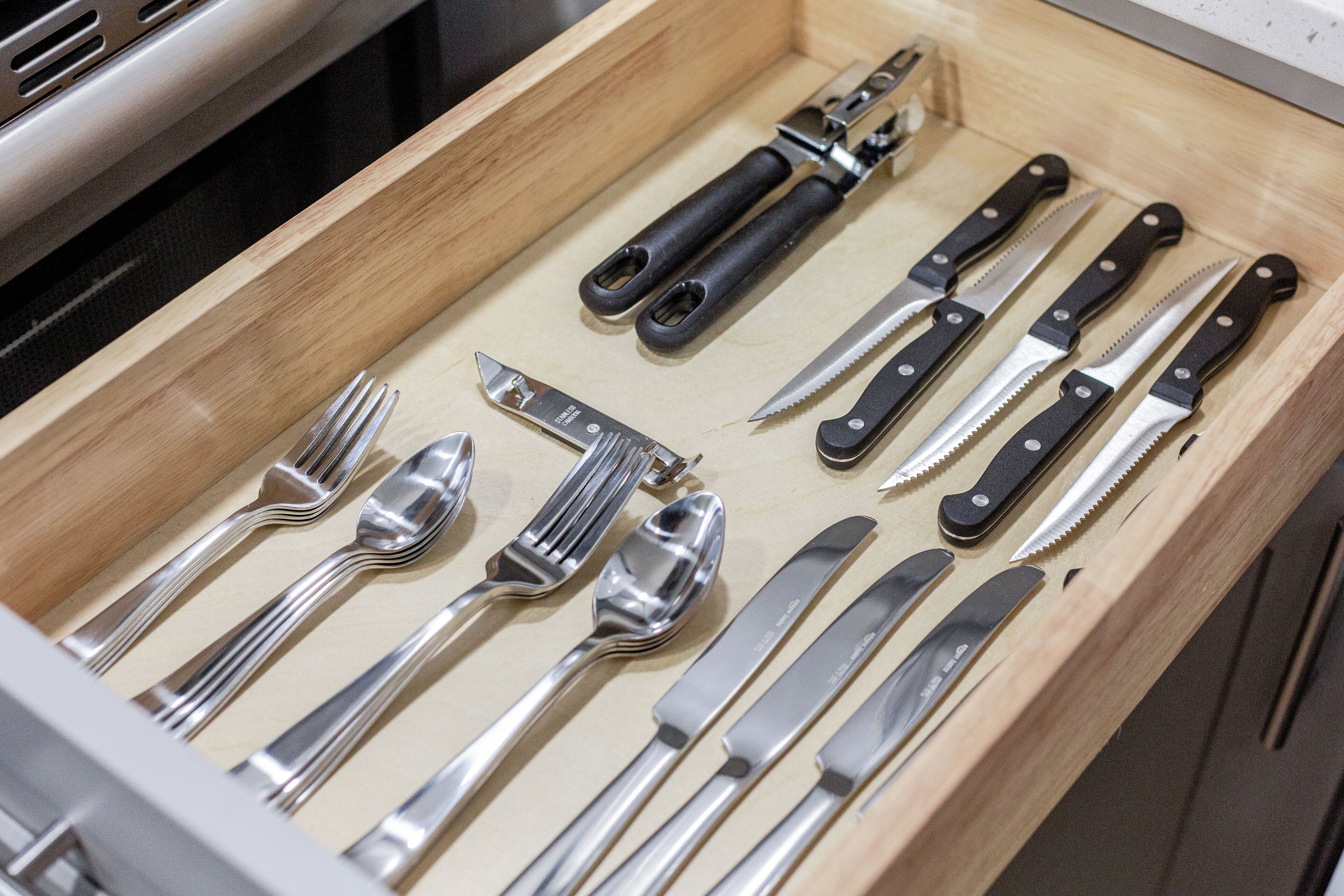A drawer containing various utensils including forks, knives, and spoons.