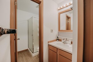 Une salle de bain avec une douche, un lavabo et un miroir avec des lumières au-dessus.