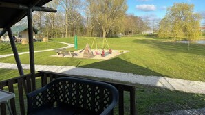 A park with a swing set, picnic tables, and a small building in the background.