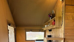 A compact kitchen with wooden cabinets, a small refrigerator, and a window providing natural light.