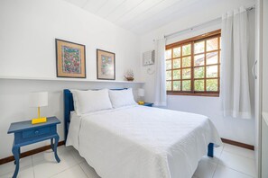 Un dormitorio con una cama, una mesita de noche, una lámpara y dos cuadros en la pared.