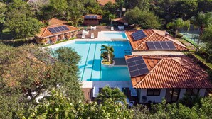 Un resort con piscina circondata da palme e pannelli solari sui tetti.