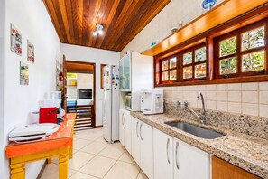 Una cocina con encimera de granito, armarios blancos, un lavamanos y una ventana con vistas a zonas verdes.